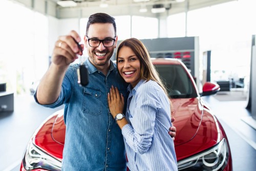 Couple with their new car smiling 